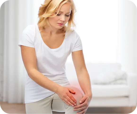 Woman holding her painful knee with visible inflammation, illustrating common symptoms of chronic patellar fat pad inflammation (Hoffa’s disease)