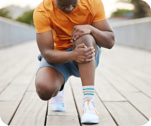 Athlete holding his knee due to pain and pressure, illustrating symptoms of Lateral Patellofemoral Compressive Syndrome (LPCS)