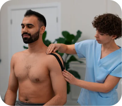 Physical therapist applying shoulder kinesio tape to a patient during evaluation for pectoralis tendon rupture treatment