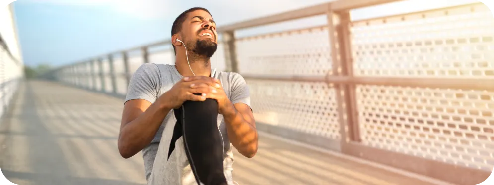 Man holding knee in pain after running, showing symptoms of a chondral defect or cartilage injury.