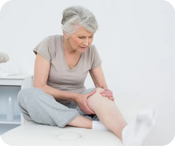 Older woman holding her knee due to severe joint pain caused by end stage osteoarthritis, highlighting symptoms and need for advanced knee treatment.