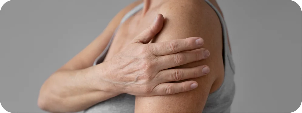 Woman holding the top of her shoulder due to AC joint pain, showing symptoms of acromioclavicular joint injury