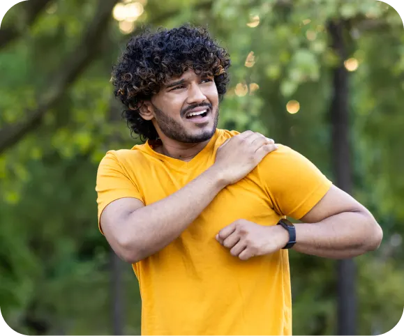 Man holding his painful shoulder outdoors, illustrating common symptoms of shoulder instability related to Bankart, ALPSA, or HAGL lesions